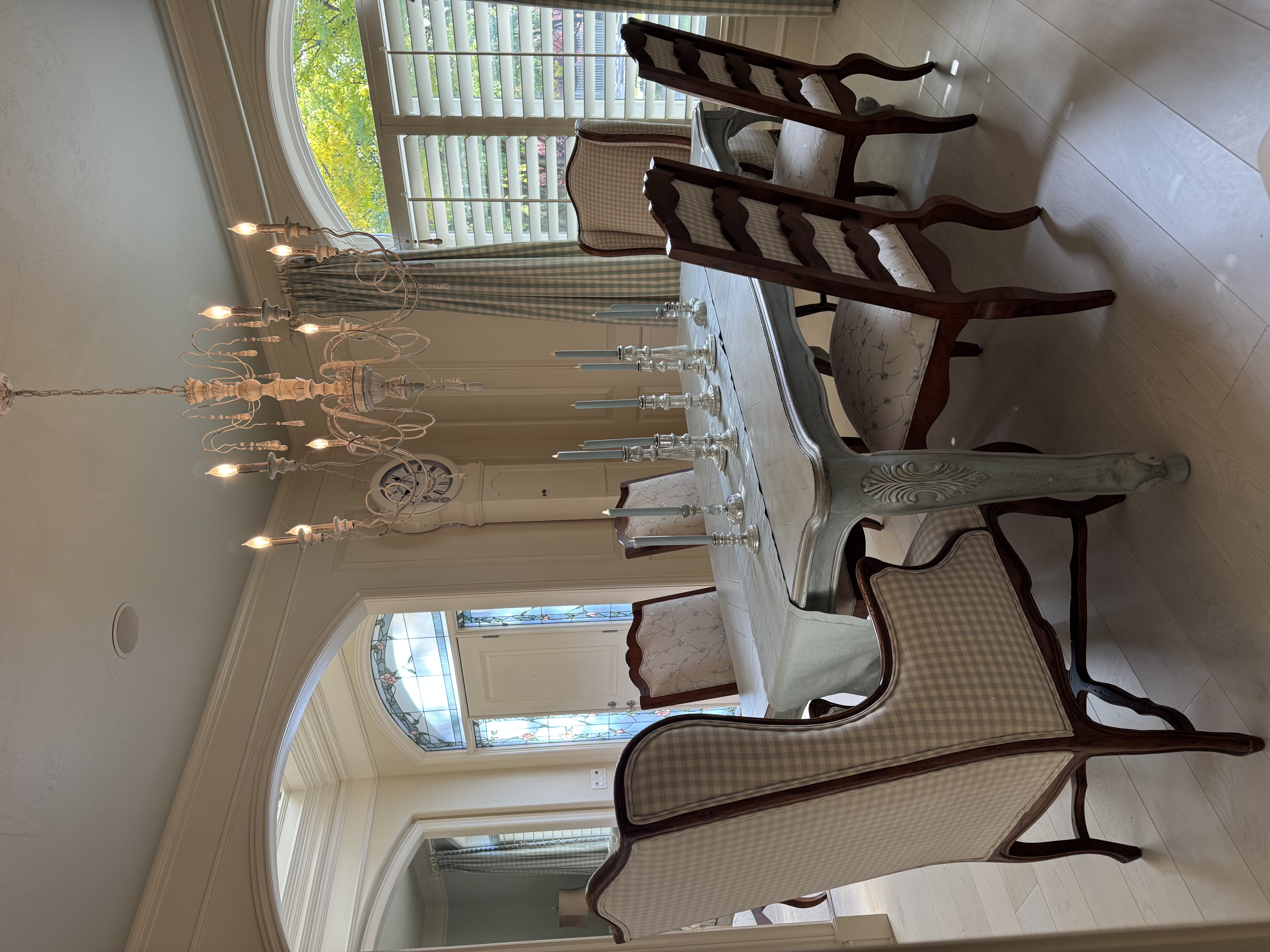 A French-style dining table with mixed upholstered chairs, silver candlesticks, and a cream chandelier.